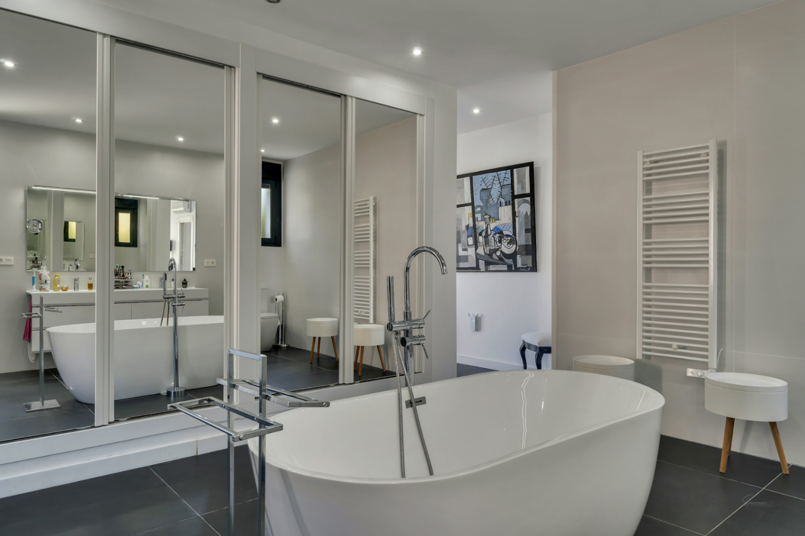 Master-Badezimmer mit freistehender Badewanne, bodenmontierter Chrom-Armatur und großen Spiegelschiebetüren für ein helles, modernes Ambiente.