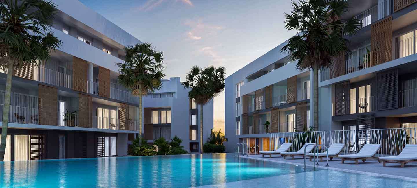 Gemeinschaftlicher Poolbereich in der Abenddämmerung mit Liegestühlen, Palmen und modernen Apartmenthäusern mit markanten Holzläden.