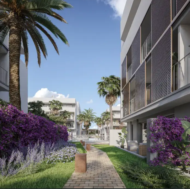 Ein gepflasterter Steinweg führt durch die gepflegte Gartenanlage mit lila Bougainvillea, Palmen und modernen Gebäudefassaden mit vertikalen Lamellen.