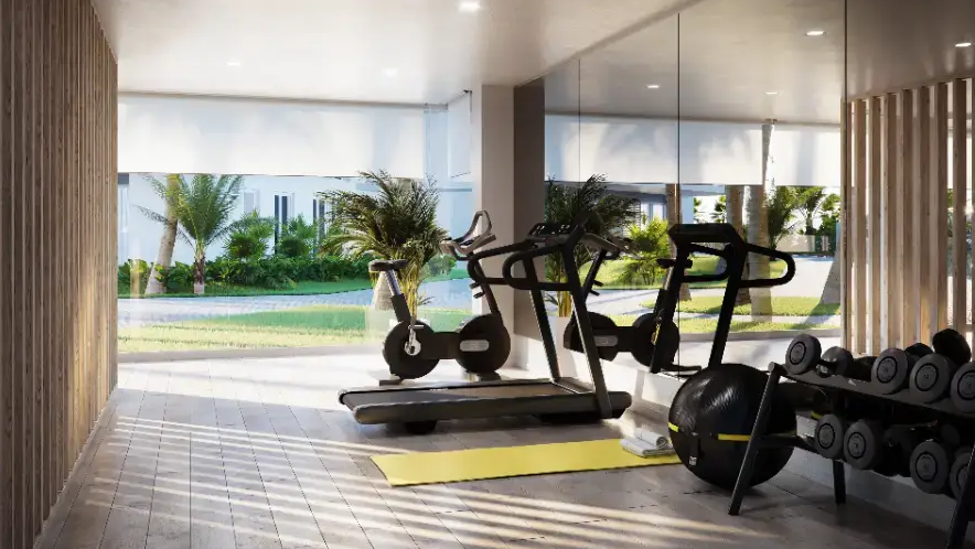 Modernes Fitnessstudio mit Kardiogeräten, Hanteln und bodentiefen Fenstern mit Blick auf die mediterranen Gärten. Ausgestattet mit Holzlamellenwänden und Einbaustrahlern.