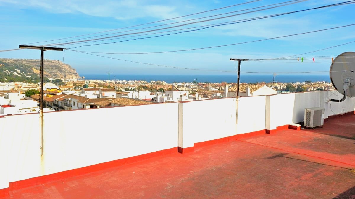 Gemeinschaftliche Dachterrasse mit rotem Bodenbelag und Panoramablick über die Altstadt von Javea bis zum Mittelmeer.