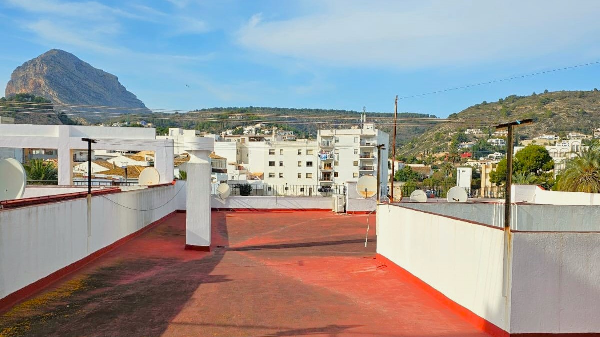 Gemeinschaftliche Dachterrasse mit rotem Bodenbelag und weitem Ausblick auf den Berg Montgó sowie die umliegende Landschaft von Javea.