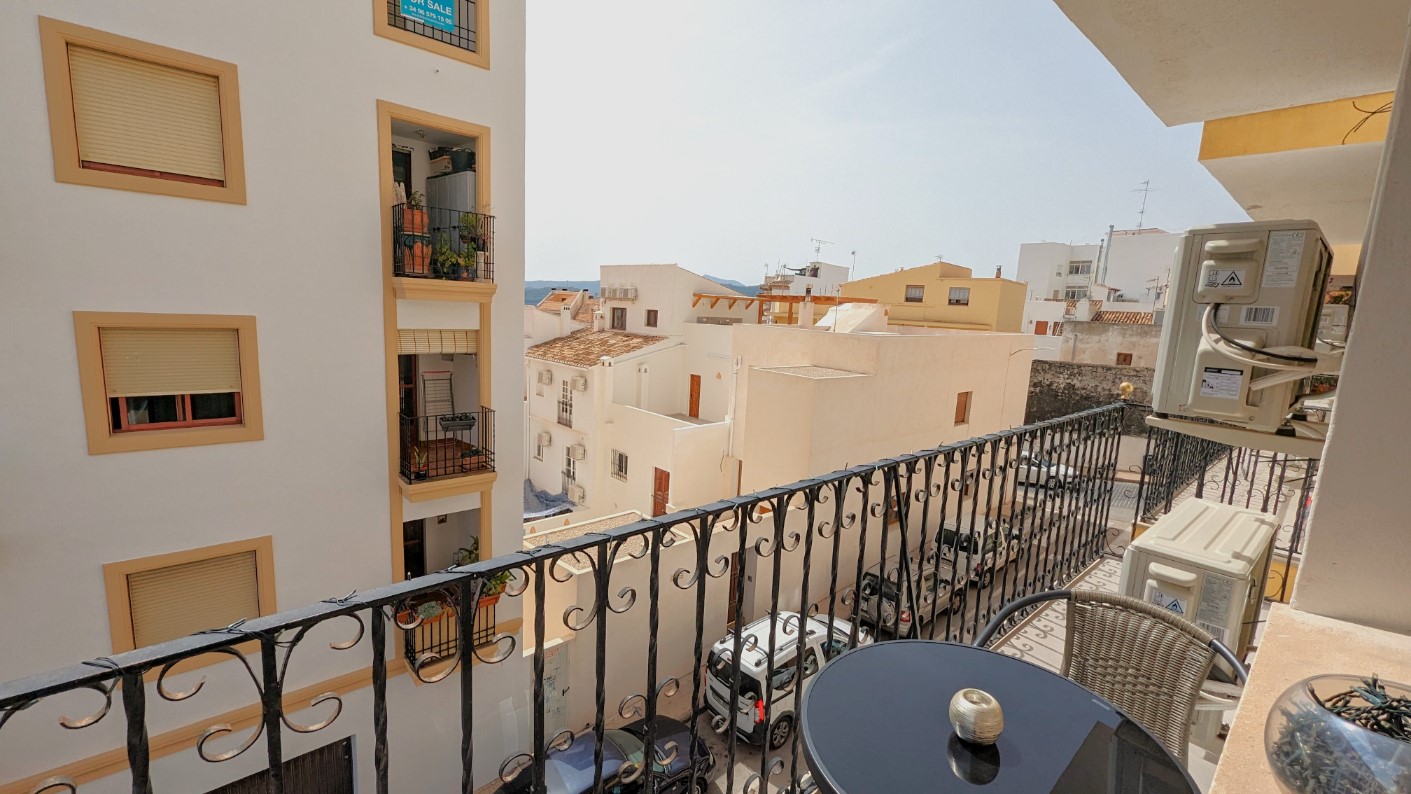 Privater Balkon mit schmiedeeisernem Geländer, kleinem Beistelltisch und Blick auf die traditionellen weißen Gebäude der Altstadt von Javea.