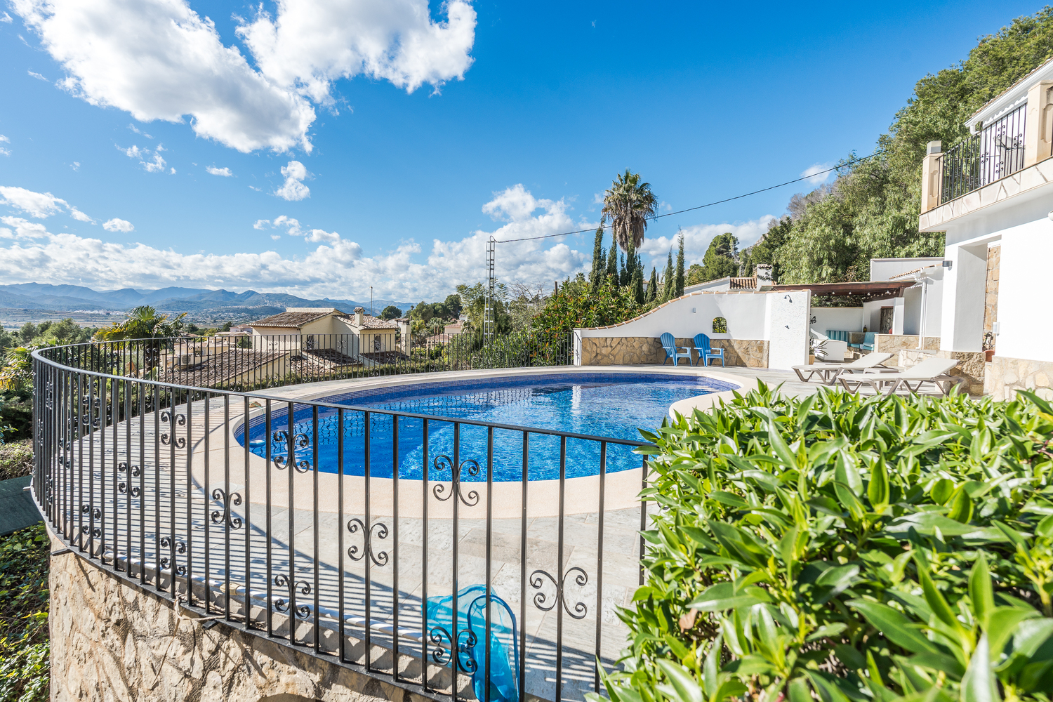 Erhöhte Terrasse mit nierenförmigem Pool, dekorativem Schmiedeeisengeländer und Panoramablick auf das Tal und die umliegenden Berge.