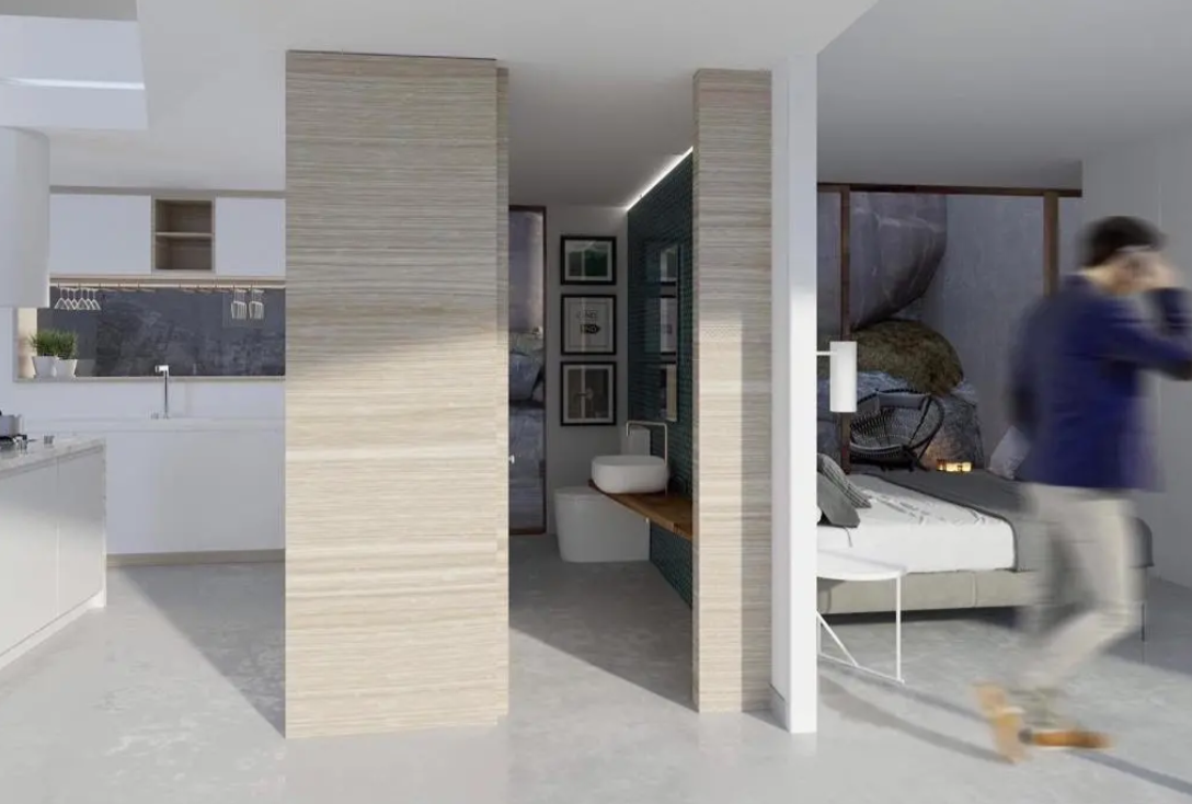 Offene Suite mit integrierter weißer Küche, En-Suite-Bad mit Aufsatzwaschbecken und Schlafzimmer mit Blick auf Felswand. Trennwände in heller Holzoptik.