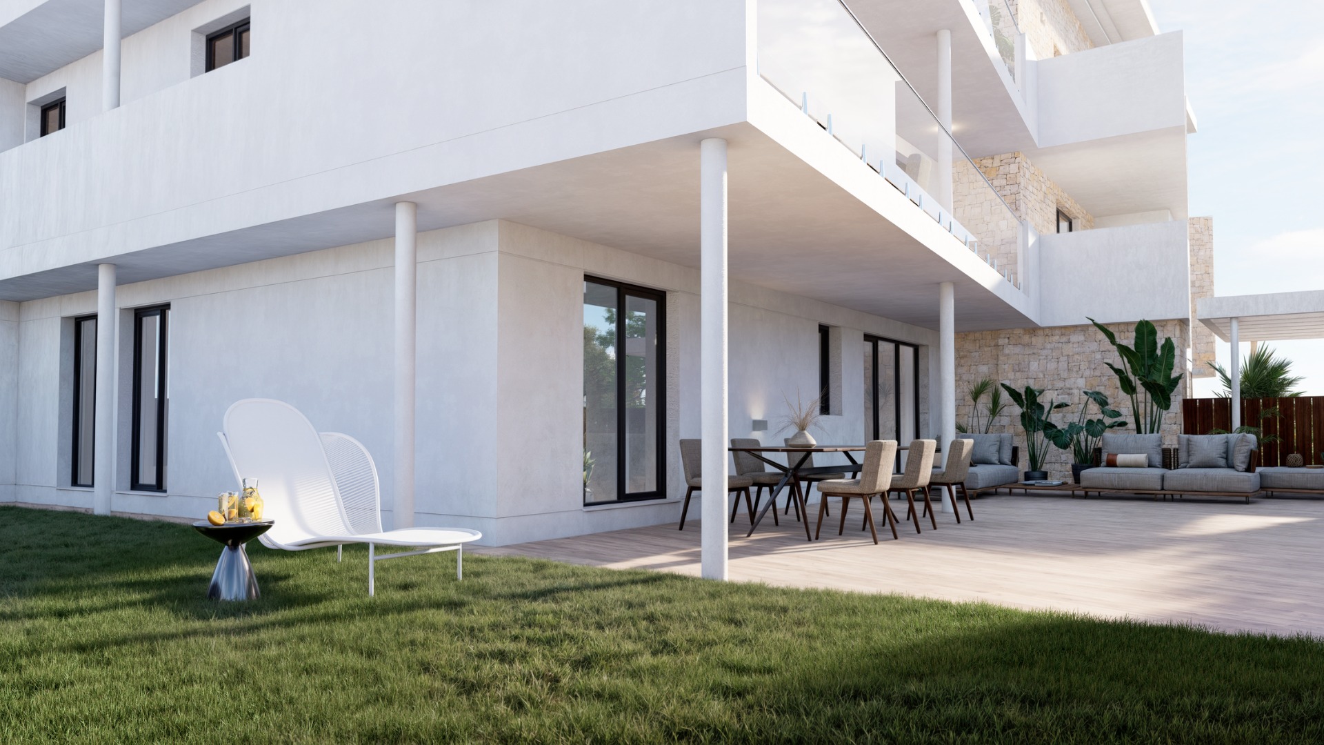 Erdgeschoss-Terrasse mit Boden in Holzoptik, privatem Rasen und modernen Möbeln. Die weiße Fassade wird durch Natursteinwände und Glasgeländer an den Balkonen ergänzt.