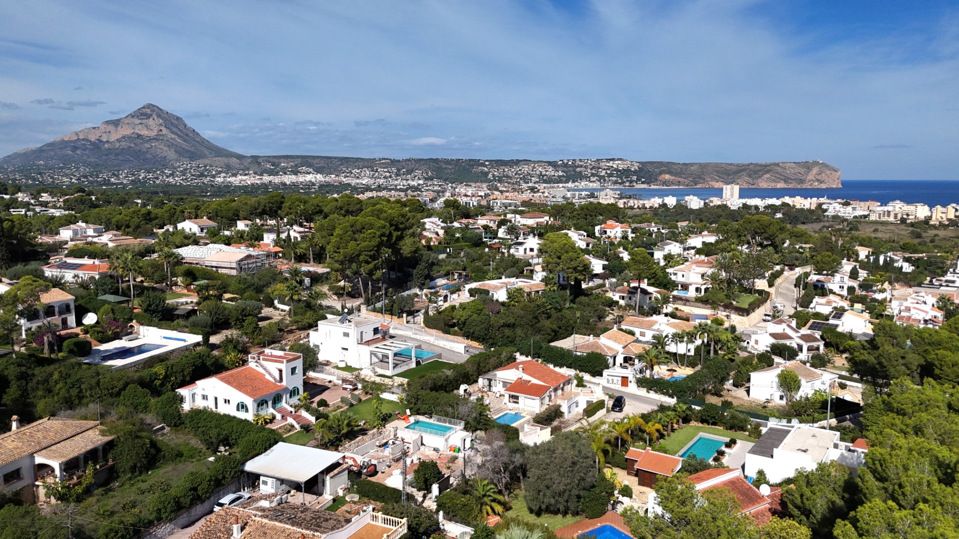 Panorama-Luftaufnahme des Viertels Toscal in Jávea mit Blick auf den Montgó, das Cabo San Antonio und die Mittelmeerküste bei klarem Himmel.