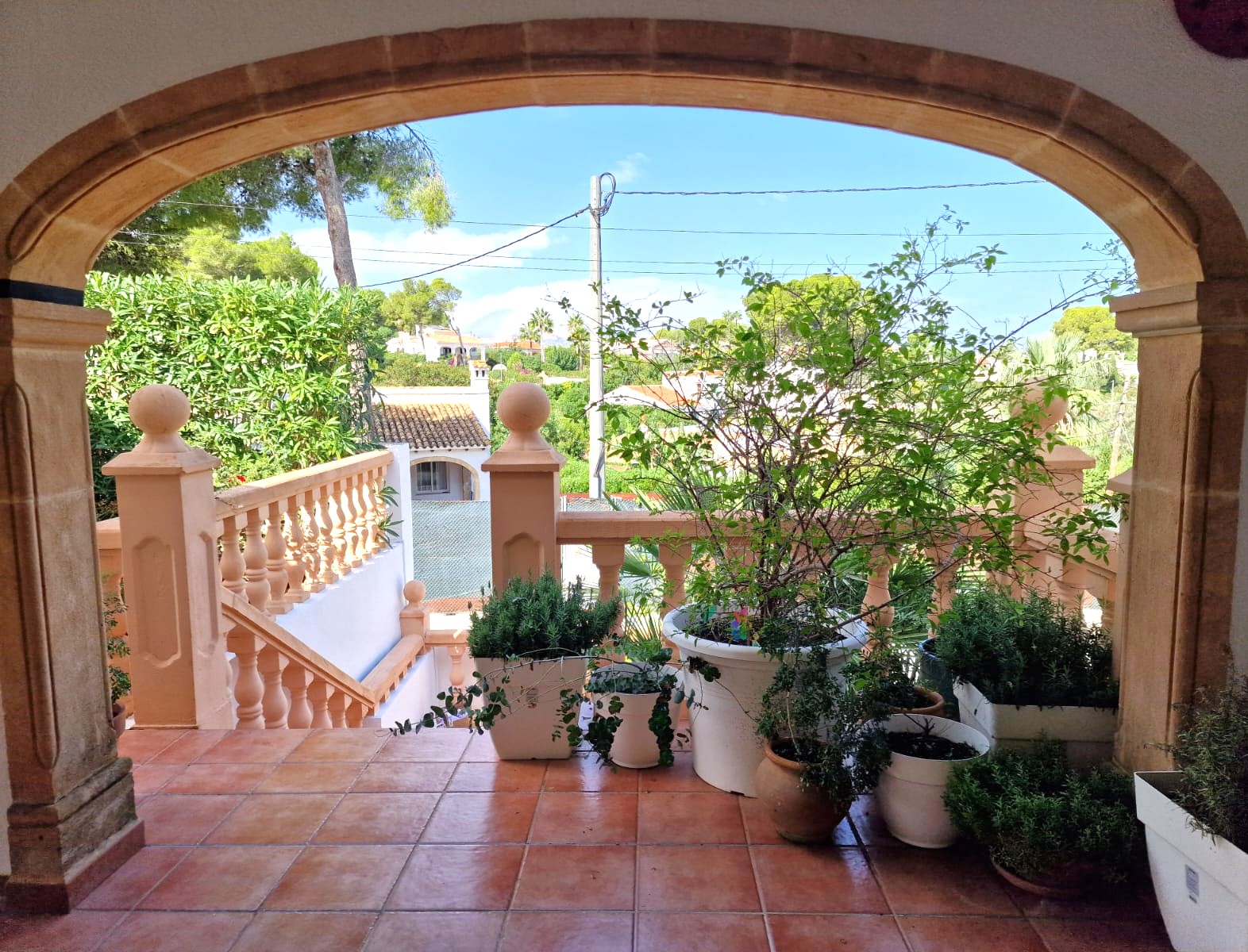 Terrasse mit traditionellem Tosca-Steinbogen, Terrakotta-Bodenbelag und Blick auf die mediterrane Landschaft und die umliegenden Villen.