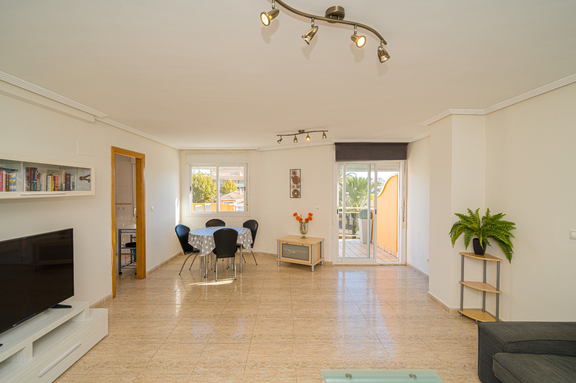 Großzügiger Wohn- und Essbereich mit hellen Fliesenböden, Deckenstrahlern und direktem Zugang zur privaten Terrasse durch Glasschiebetüren.