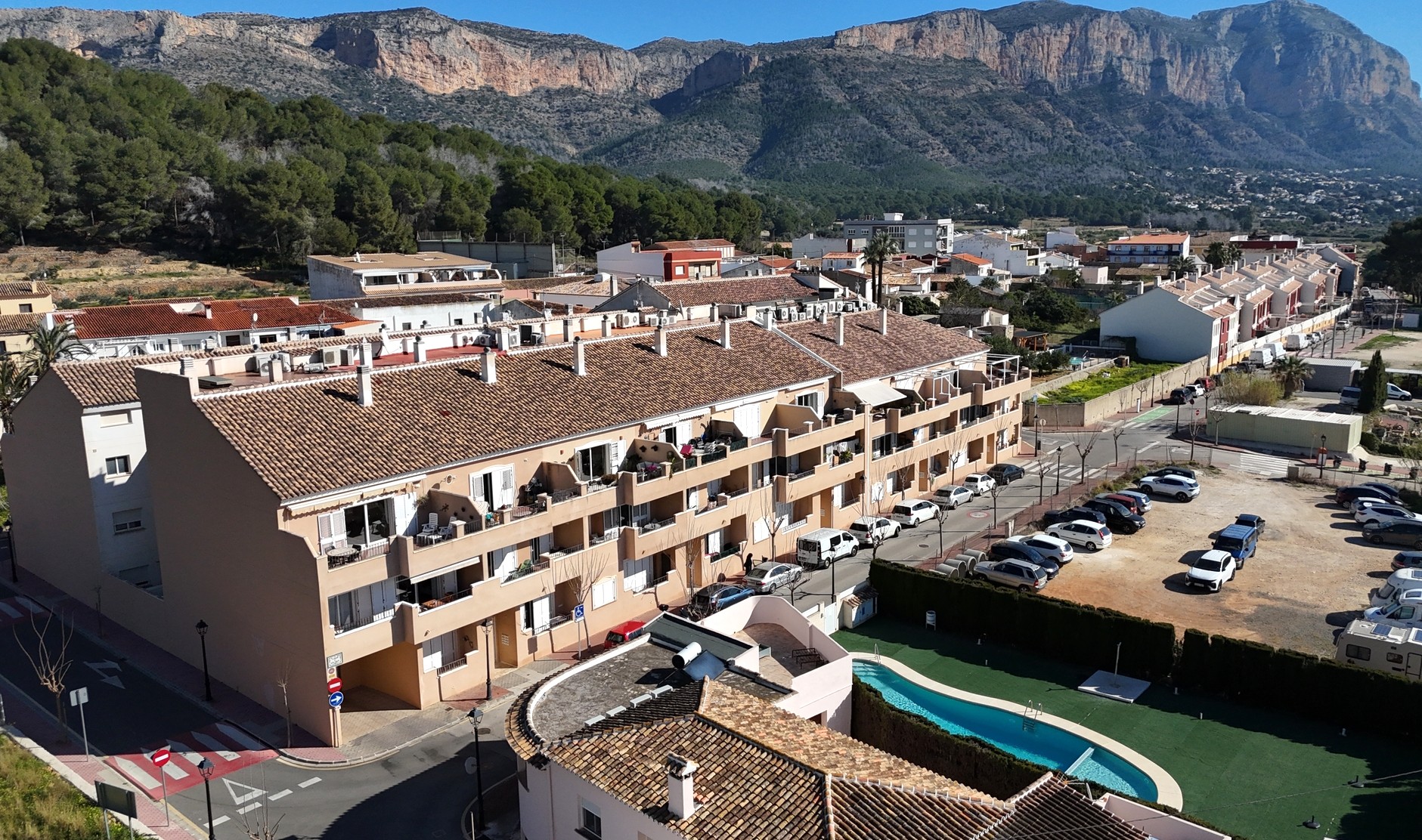 Erhöhte Ansicht der Anlage in Jesús Pobre mit Gemeinschaftspool, Terrakottadächern und Blick auf das beeindruckende Montgó-Massiv.