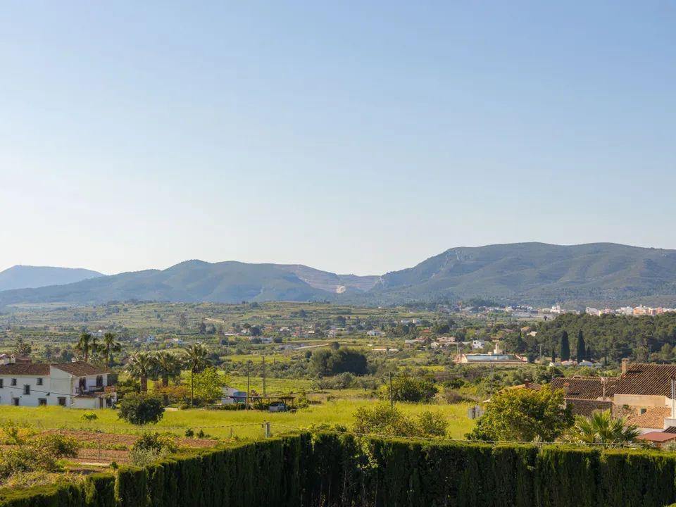 Freier Panoramablick über das Tal und die Berge der Costa Blanca, der die ländliche Landschaft und die mediterrane Vegetation von der Terrasse aus zeigt.