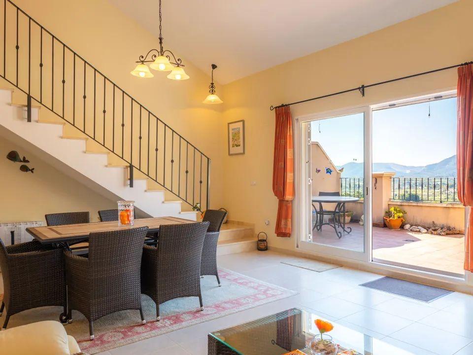 Heller Essbereich mit schmiedeeiserner Treppe und Zugang zu einer Terrasse mit Panoramablick auf die umliegende Berglandschaft.