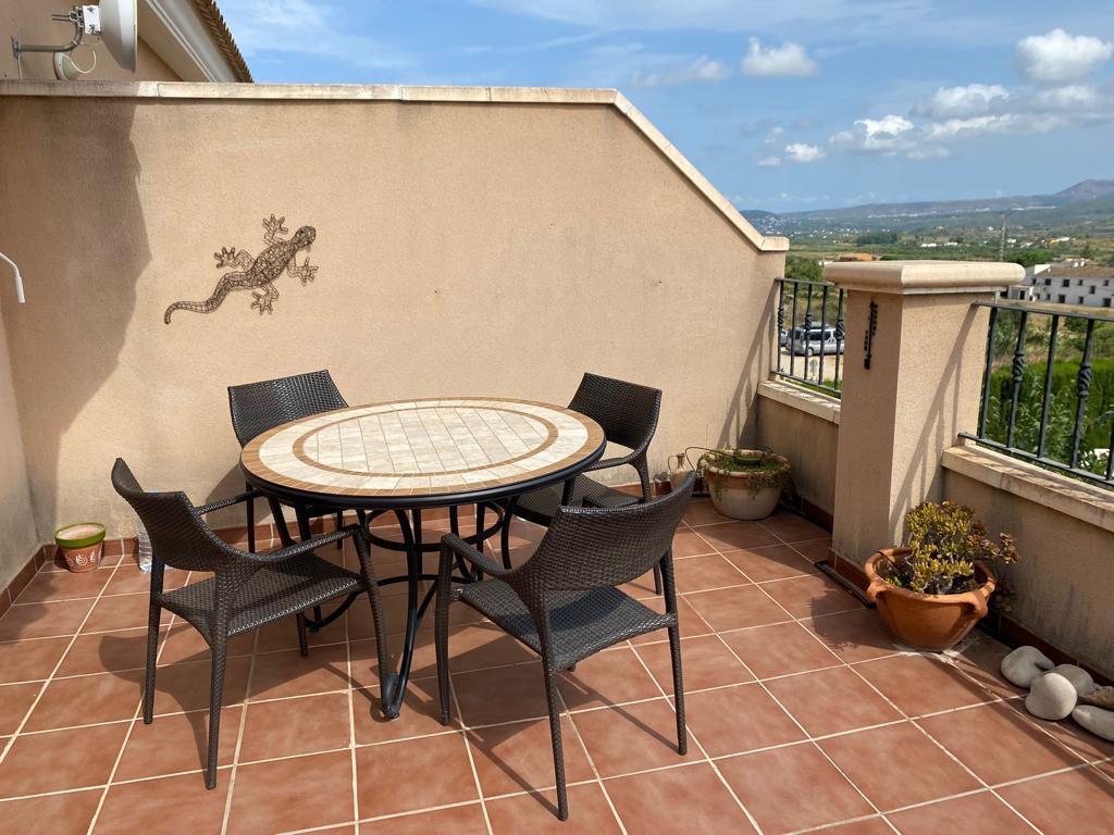 Terrasse mit Terrakotta-Fliesen, Mosaiktisch und vier Stühlen, die einen weiten Blick auf die umliegende Landschaft bietet.