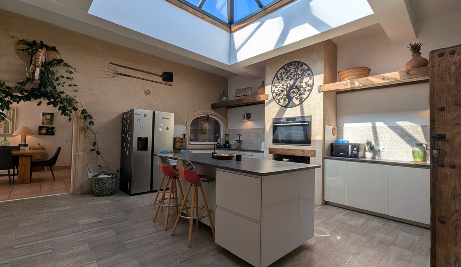 Moderne Küche mit einer markanten Glaskuppel, einer zentralen Insel mit Barhockern und rustikalen Steinwänden mit traditioneller Dekoration.