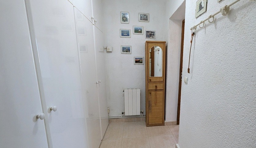 Flur oder Ankleidebereich mit deckenhohen weißen Einbauschränken, einem Korbschrank mit Spiegel und einem wandmontierten Heizkörper.