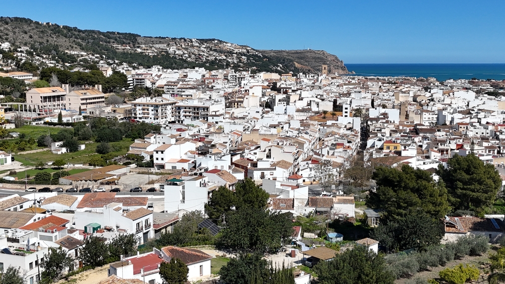 Erhöhter Panoramablick auf die Altstadt von Javea mit ihren traditionellen weißen Häusern, dem Kirchturm San Bartolomé und dem weiten Mittelmeerhorizont.