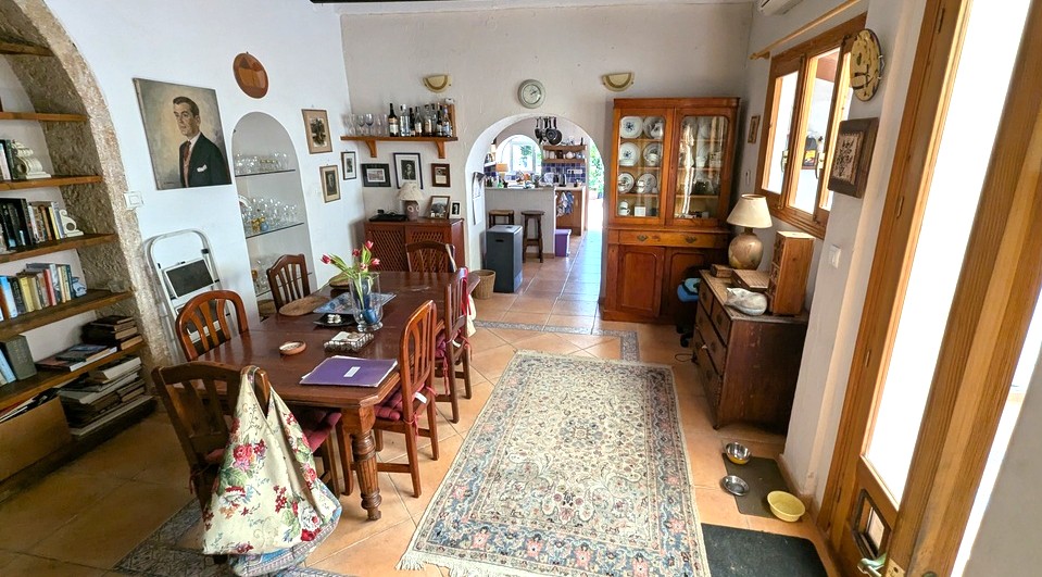 Großzügiges Esszimmer mit traditionellen Terrakottafliesen, Massivholztisch und authentischen Tosca-Steinbögen mit integrierten Regalen und Blick zur Küche.
