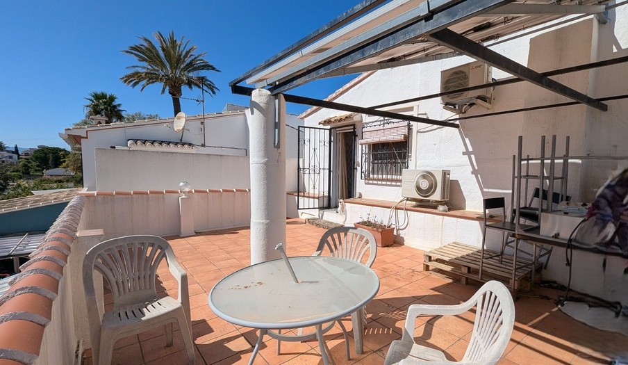 Südterrasse im ersten Stock mit Terrakottaboden, einer Metallpergola und Außenklimageräten, die einen Blick auf die umliegende Landschaft und Palmen bietet.