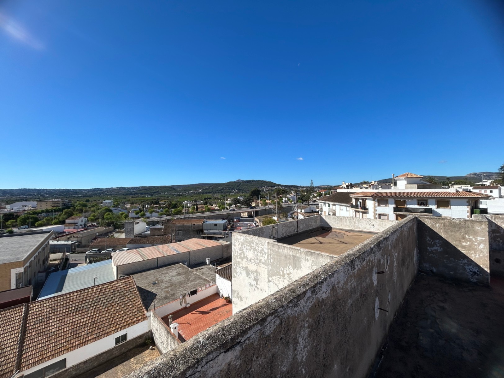 Erhöhte Perspektive von der gemeinschaftlichen Dachterrasse mit Panoramablick auf das Stadtbild von Jávea und die fernen Berge.