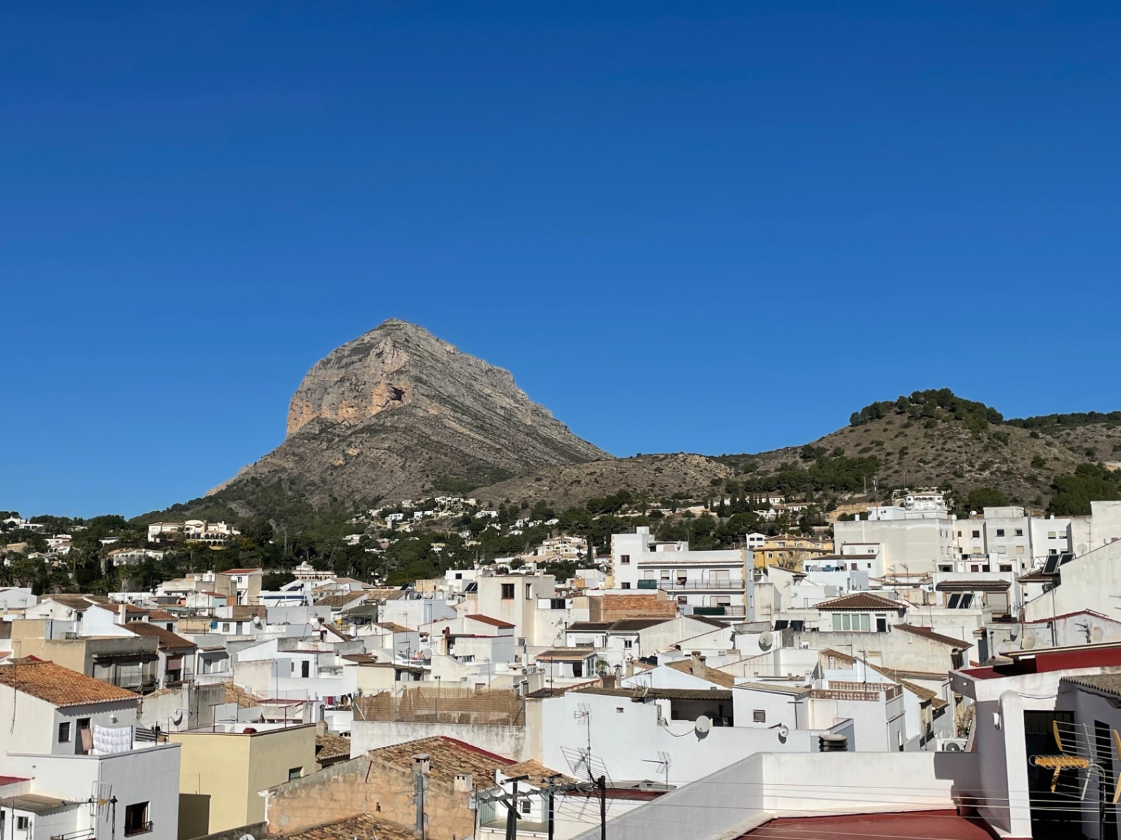 Panoramablick von der Dachterrasse auf den Berg Montgó und die Altstadt von Jávea mit ihren traditionellen weißen Fassaden und Ziegeldächern.