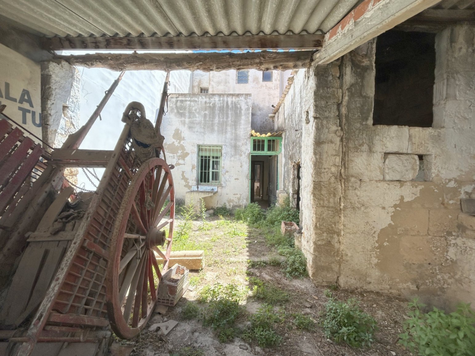 Hinterhof mit antikem Holzwagen und originalen Steinmauern. Außenbereich mit separatem Zugang und großem Potenzial für eine Sanierung.