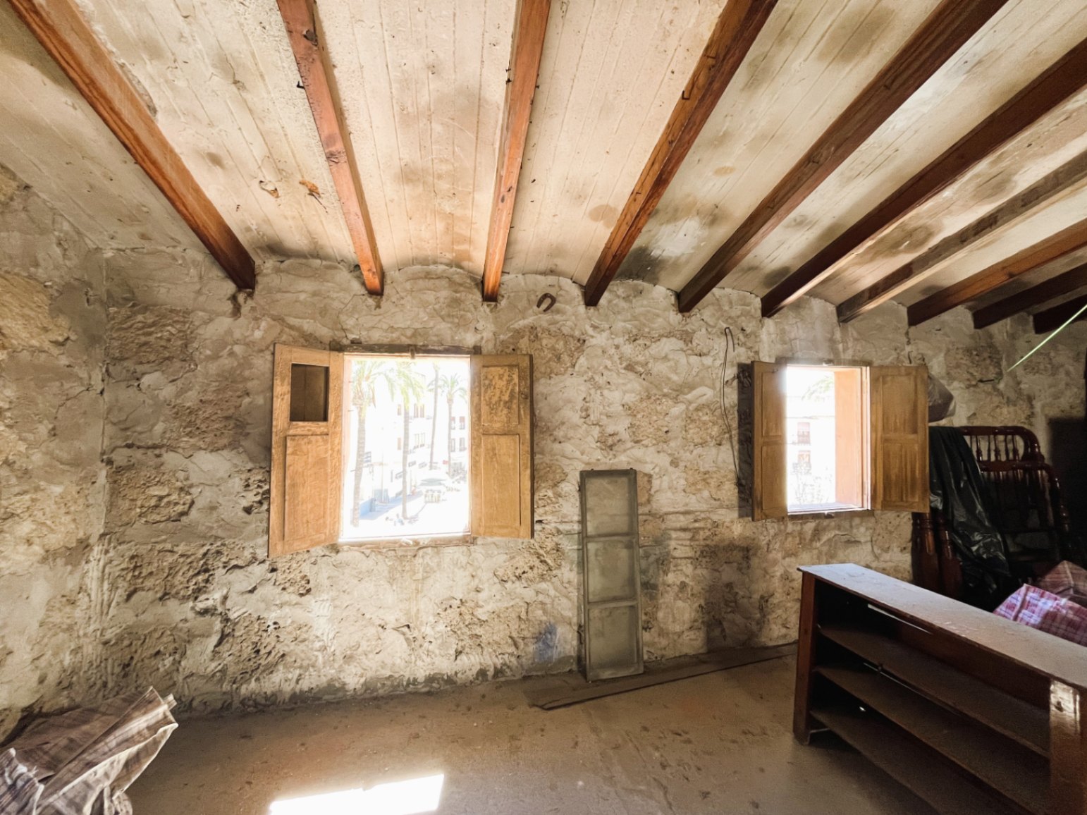 Zimmer mit originalen Natursteinwänden und Holzbalkendecke. Zwei Fenster mit Holz-Schlagläden bieten natürliches Licht und Ausblick auf die historische Altstadt.
