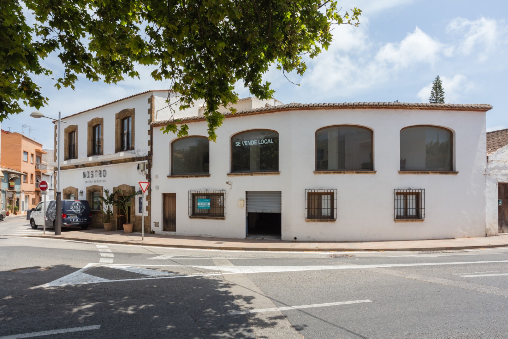 Außenansicht einer Eckfassade in Jávea mit traditionellen Tosca-Steinrahmen, großen Fenstern im Obergeschoss und zweistöckiger mediterraner Architektur.