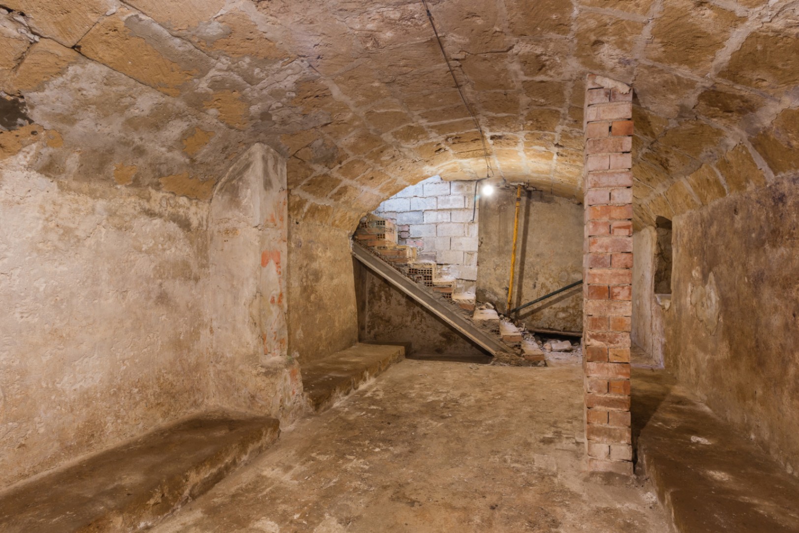 Kellergeschoss mit originalen Gewölbedecken aus Tosca-Stein und Sichtziegelpfeilern. Rustikaler Raum mit Treppenzugang, ideal als Weinkeller oder Lounge.