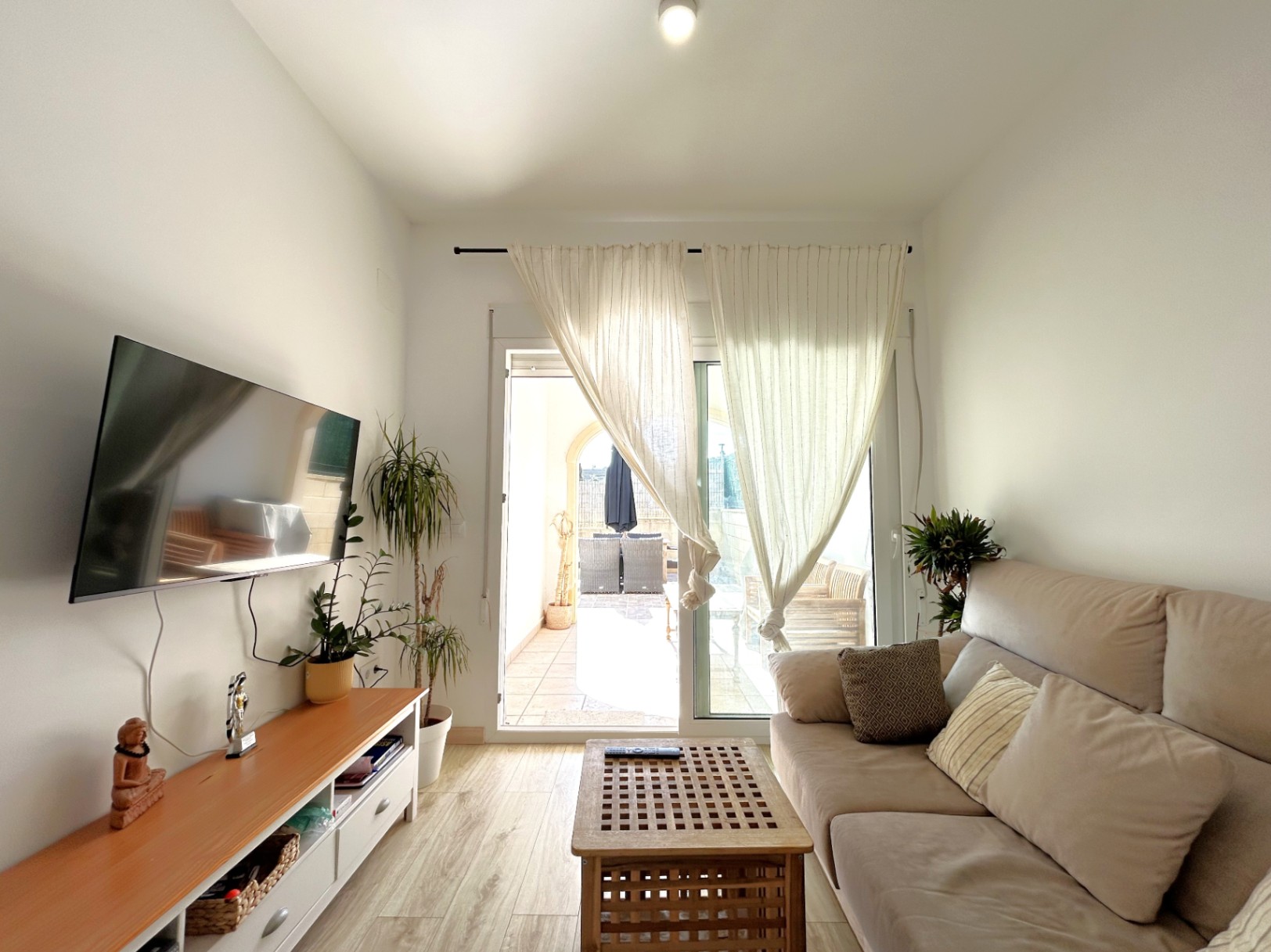 Helles Wohnzimmer mit direktem Zugang zur privaten Terrasse, ausgestattet mit Bodenbelag in Holzoptik und großen Glasschiebetüren.