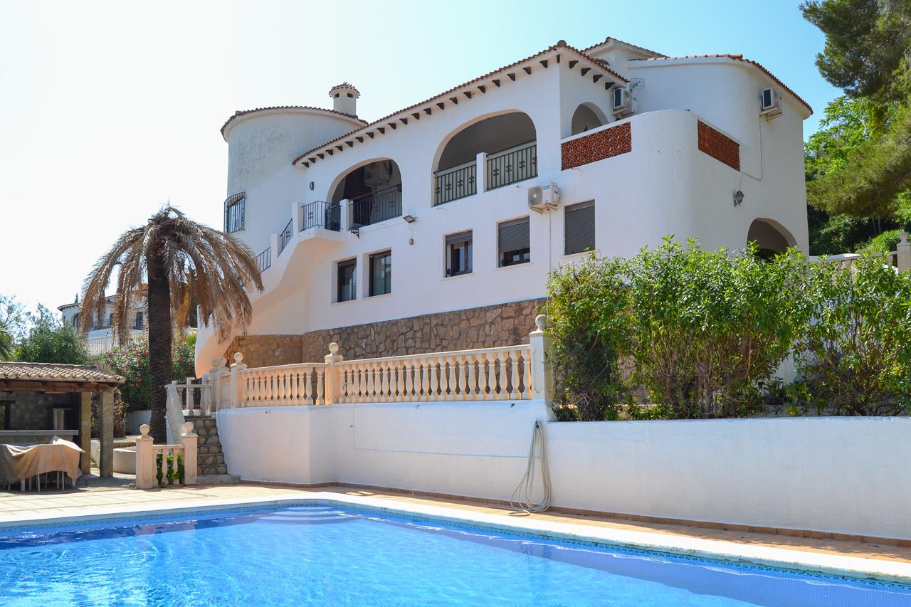 Außenansicht der Villa mit privatem Pool, weißen Fassaden im mediterranen Stil und bogenförmigen Terrassen über einem Sockel aus Naturstein.