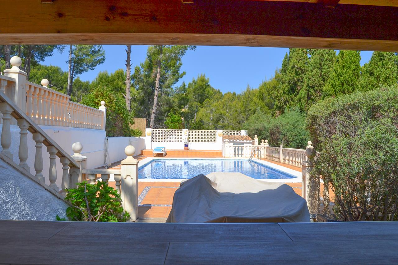 Blick auf den 12x6 Meter großen Pool vom überdachten Barbereich aus, mit Terrakotta-Terrassen, Steinbalustraden und mediterraner Vegetation.