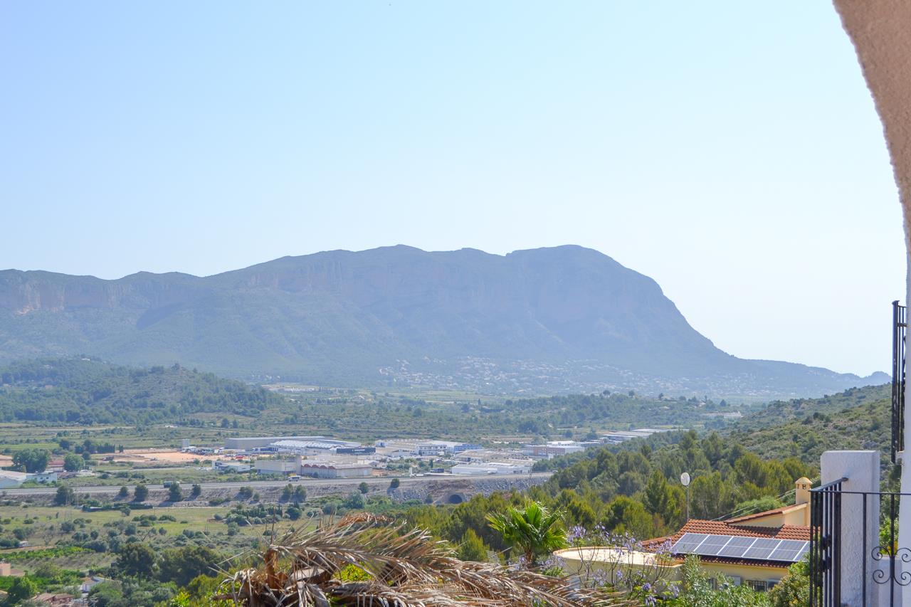 Panoramablick über das Tal und die Bergkette von der Terrasse aus. Die Landschaft ist geprägt von üppiger mediterraner Vegetation und einem weiten, hellen Horizont.