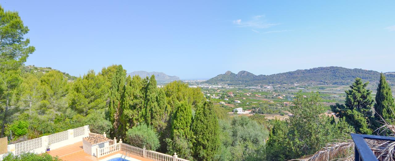 Weitläufiger Panoramablick über das grüne Tal bis hin zum Meer, mit Sicht auf den tiefer gelegenen Poolbereich und die klassische Steinbalustrade.