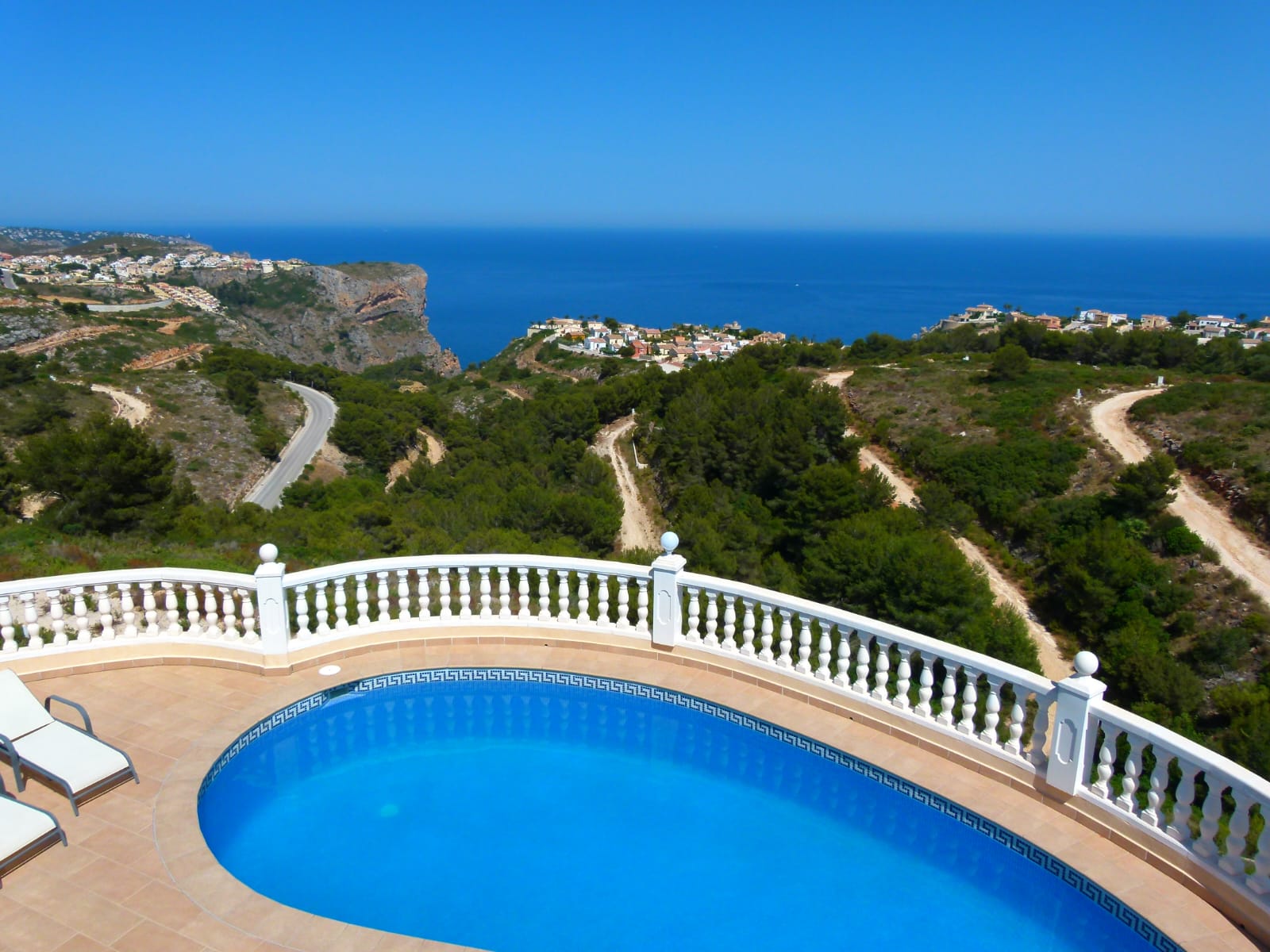 Blick auf den privaten Pool mit weißem Geländer und Panoramablick auf die Küste und die Vegetation.