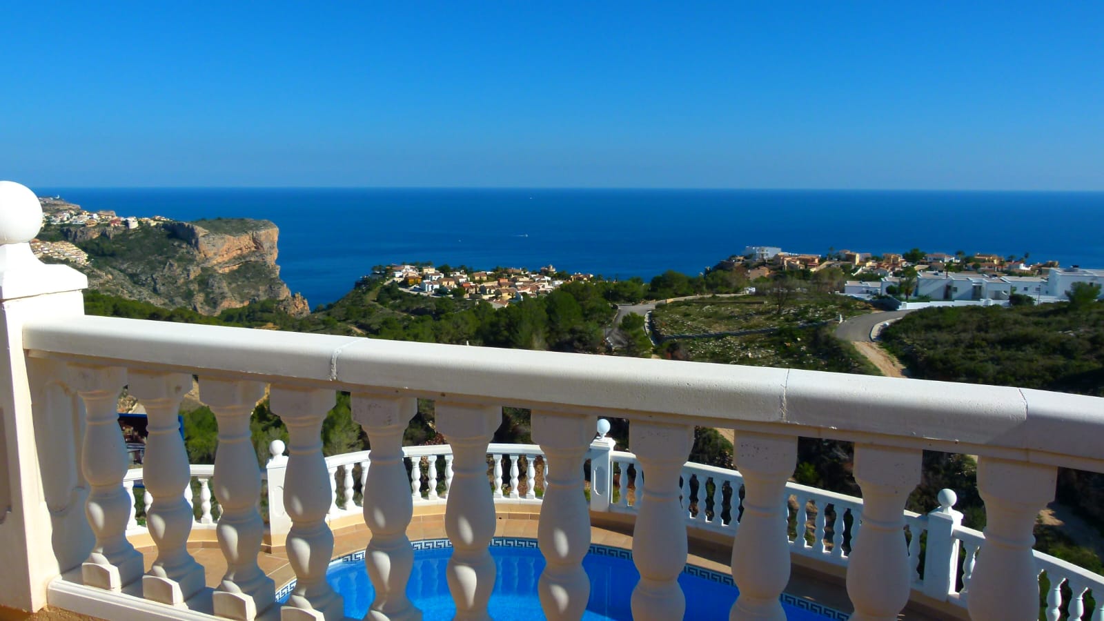 Blick von der Terrasse mit weißer Balustrade auf den Pool und das Mittelmeer in Cumbre del Sol.