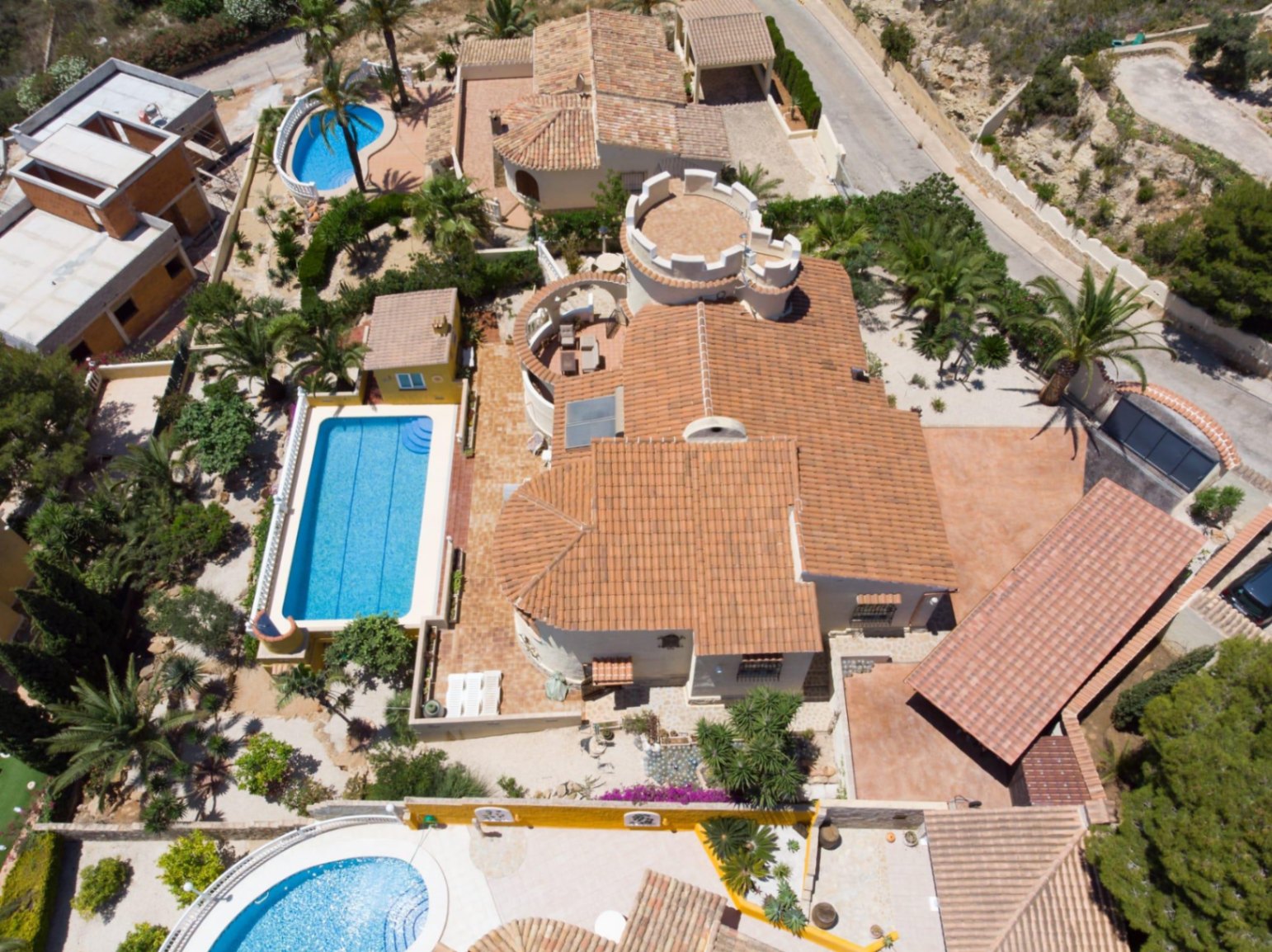 Luftaufnahme der Villa mit markanter Turmarchitektur, einem 10x4 Meter großen Pool und großzügigen Terrassenflächen inmitten eines mediterranen Gartens.
