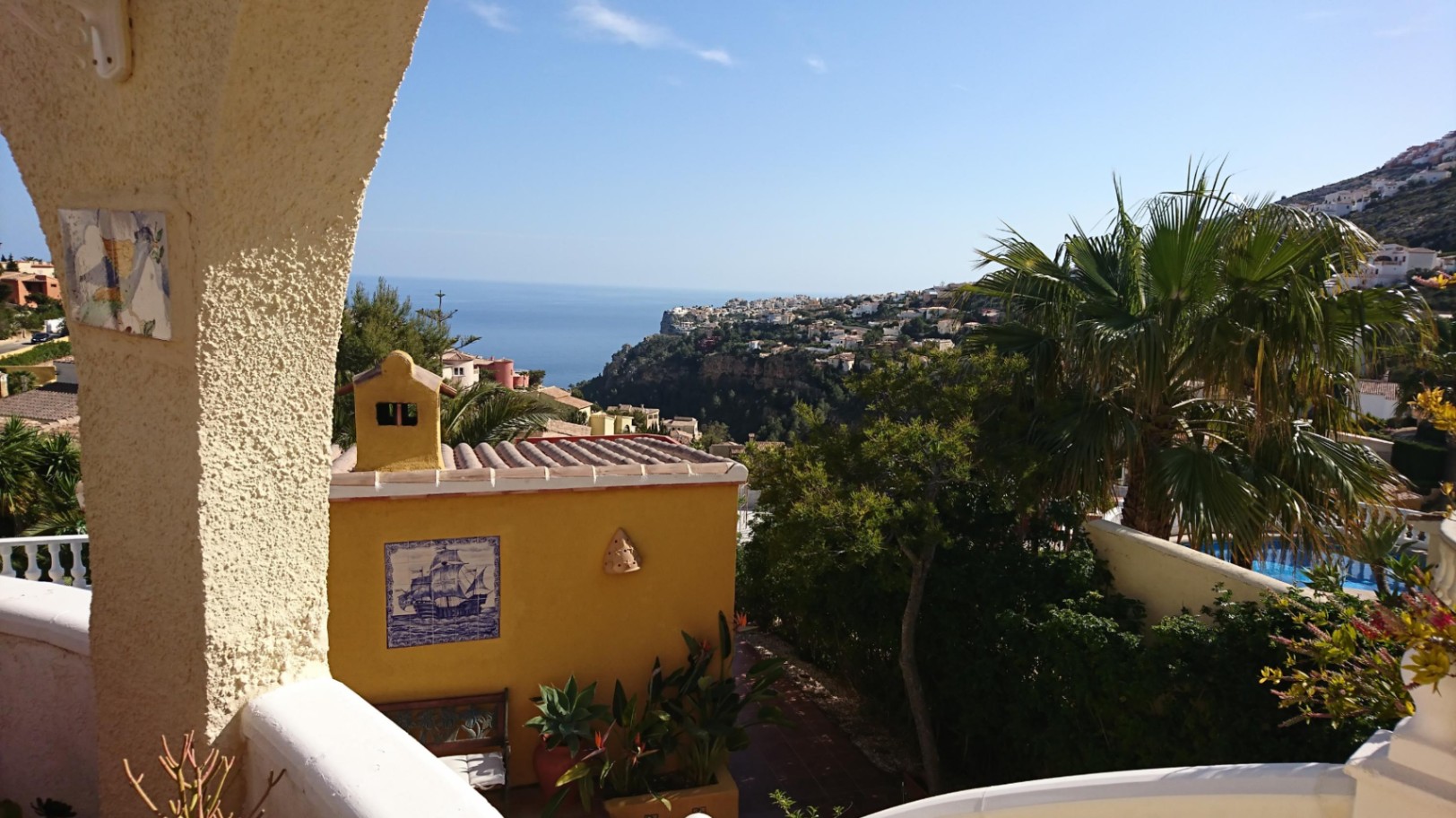 Panoramablick auf das Mittelmeer von der Terrasse, eingerahmt von traditionellen Rundbögen und umgeben von üppiger mediterraner Vegetation.