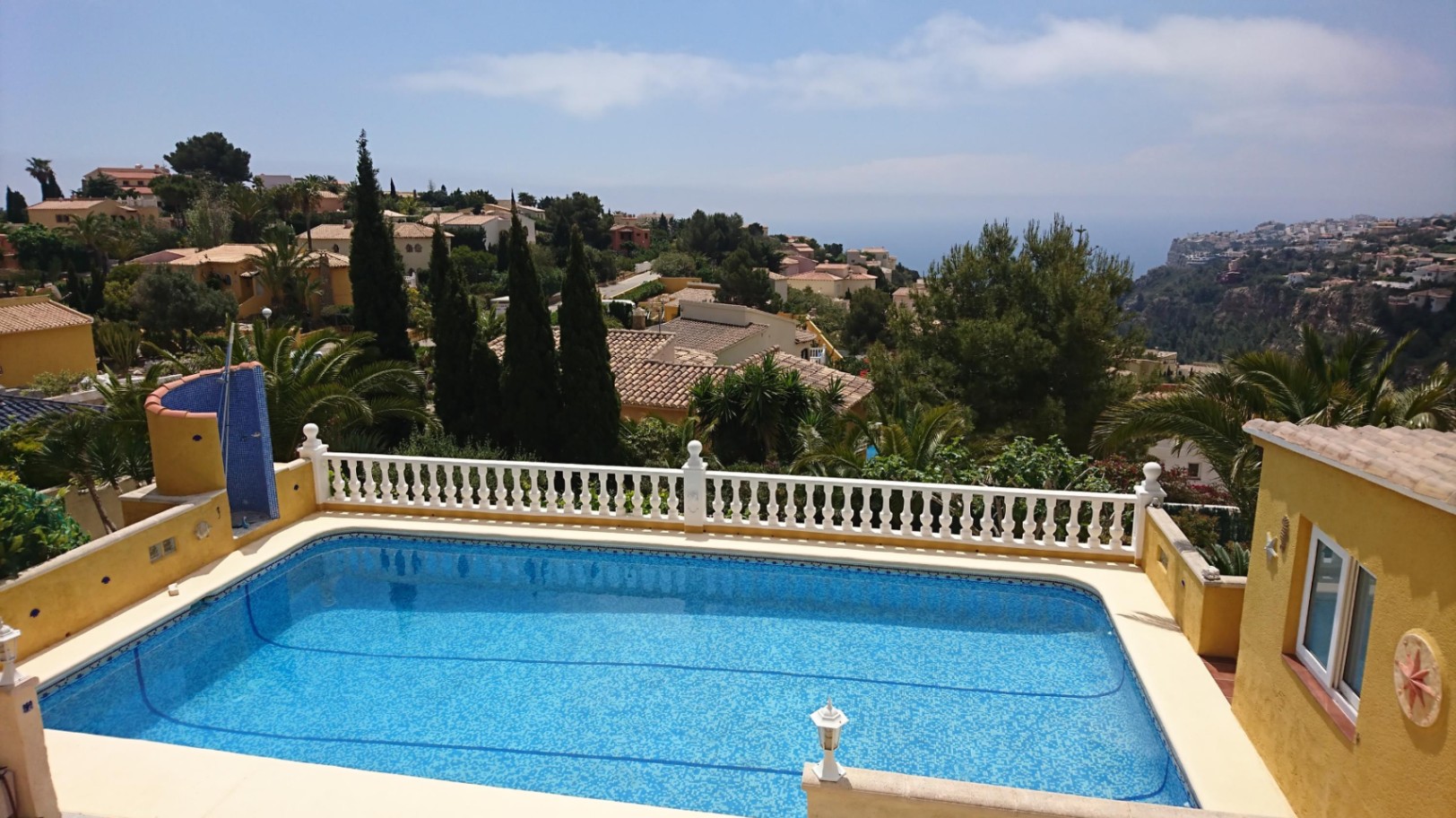 Rechteckiger 10x4m großer Pool mit blauen Mosaikfliesen, weißer Balustrade und weitem Blick über das Mittelmeer sowie die Küstenlandschaft von Cumbre del Sol.