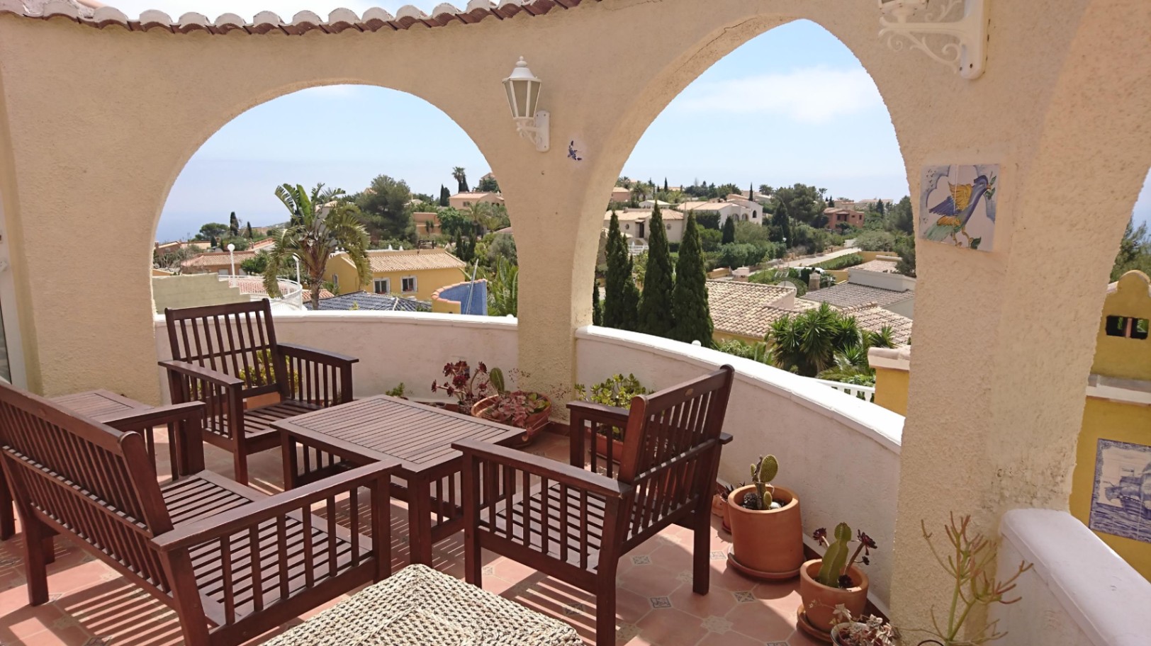 Rundterrasse mit mediterranen Rundbögen, Holzmöbeln und weitem Blick auf das Meer und die Siedlung Cumbre del Sol.