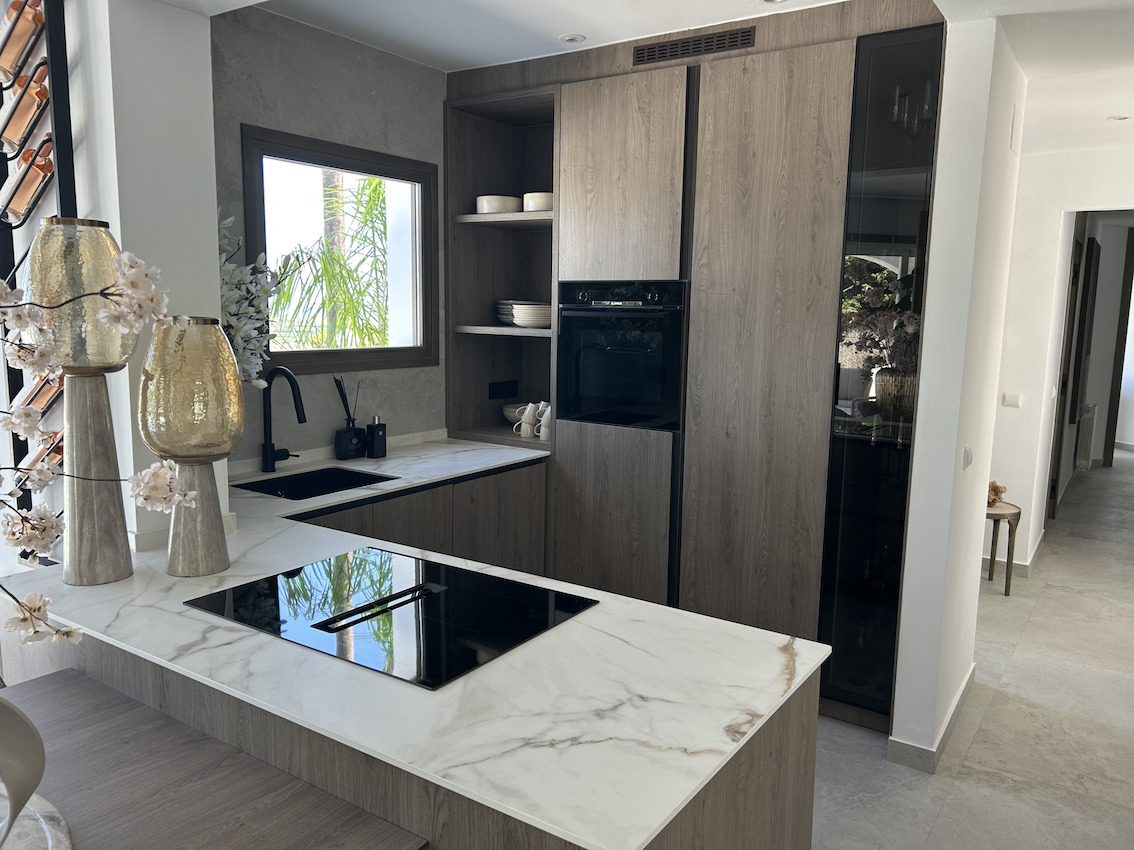 Einbauküche mit Holzfronten, Arbeitsplatten in Marmoroptik und Induktionskochfeld mit integriertem Dunstabzug.
