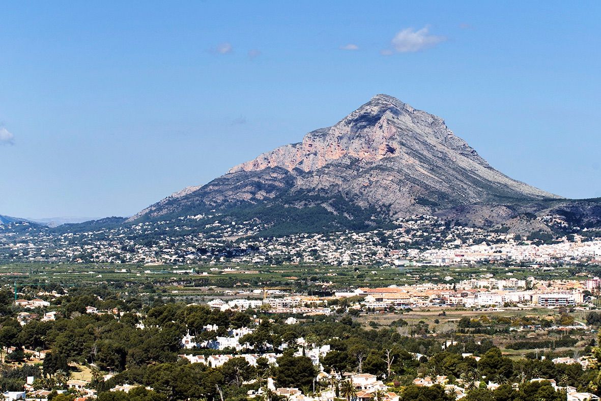 Panoramablick auf den Berg Montgó und das Tal von Jávea, der die mediterrane Landschaft und die umliegenden Wohngebiete unter klarem Himmel zeigt.