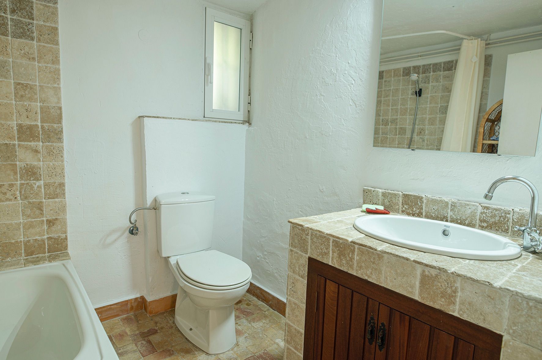 Rustikales Badezimmer mit einem Waschtisch aus Natursteinfliesen, dunklem Holzunterschrank, weißen Sanitäranlagen und Einbaubadewanne.