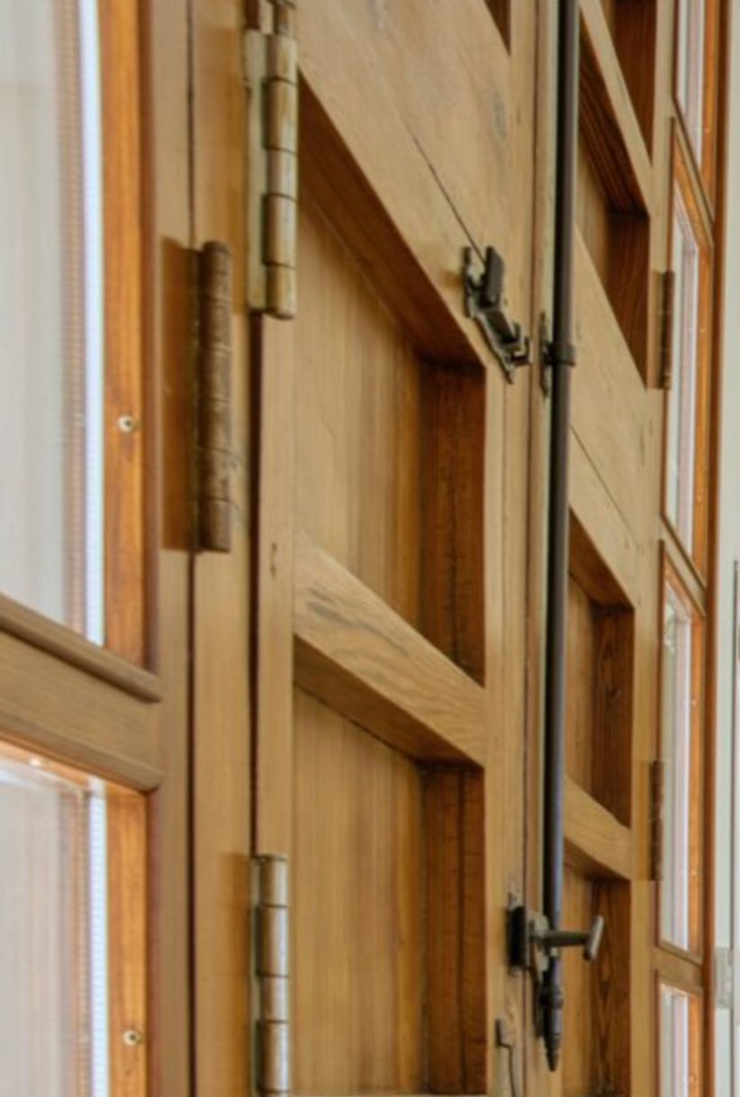 Detailaufnahme der Massivholz-Tischlerarbeiten mit traditionellen Metallscharnieren und Basküle-Verschluss, die die hochwertige handwerkliche Qualität zeigt.