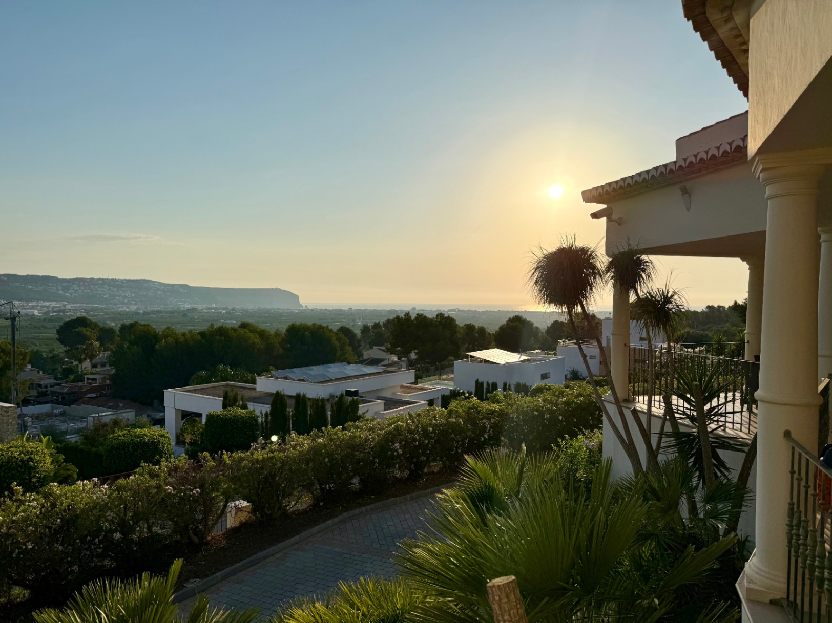 Panoramablick von der oberen Terrasse auf das Mittelmeer bei Sonnenuntergang, mit klassischen Säulen und der gepflegten Umgebung der Urbanisation Piver.